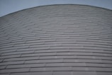 Rows of horizontally aligned, overlapping metal panels form a curved surface. The design gives a sense of uniformity and modern architecture.