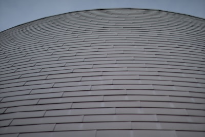 Rows of horizontally aligned, overlapping metal panels form a curved surface. The design gives a sense of uniformity and modern architecture.