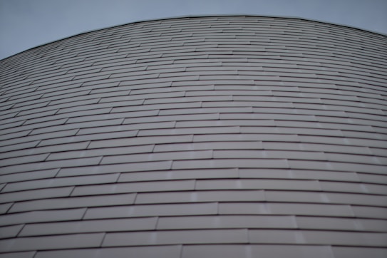 Rows of horizontally aligned, overlapping metal panels form a curved surface. The design gives a sense of uniformity and modern architecture.