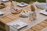 A rustic wooden table set outdoors with terracotta plates, eucalyptus garlands, and colorful seasonal dishes.