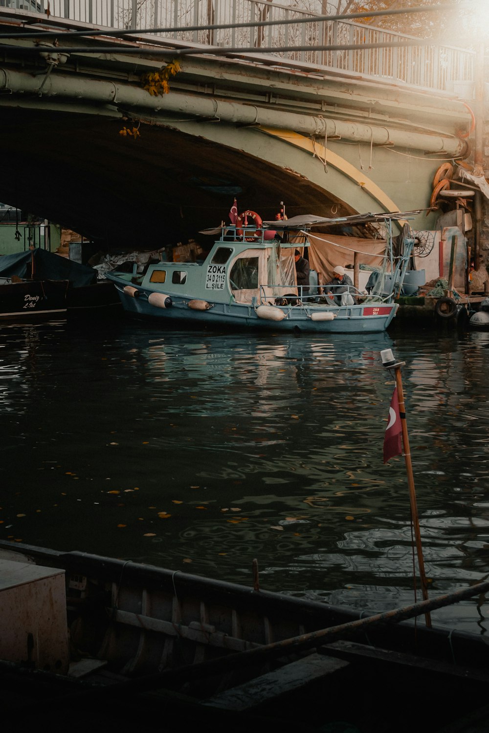 barco branco e azul na água sob a ponte durante o dia