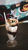 Close-up of a creamy chocolate shake topped with whipped cream and a cherry.