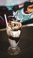 A refreshing vanilla milkshake with a striped straw and a sprinkle of chocolate shavings.