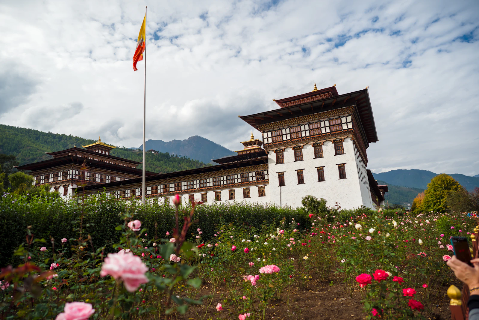 Tashichho Dzong in Thimphu behind its rose garden, the national flag flying from a tall pole beside the walls