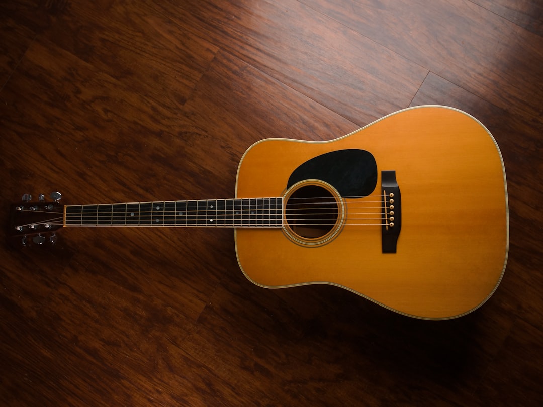 brown acoustic guitar on brown wooden floor