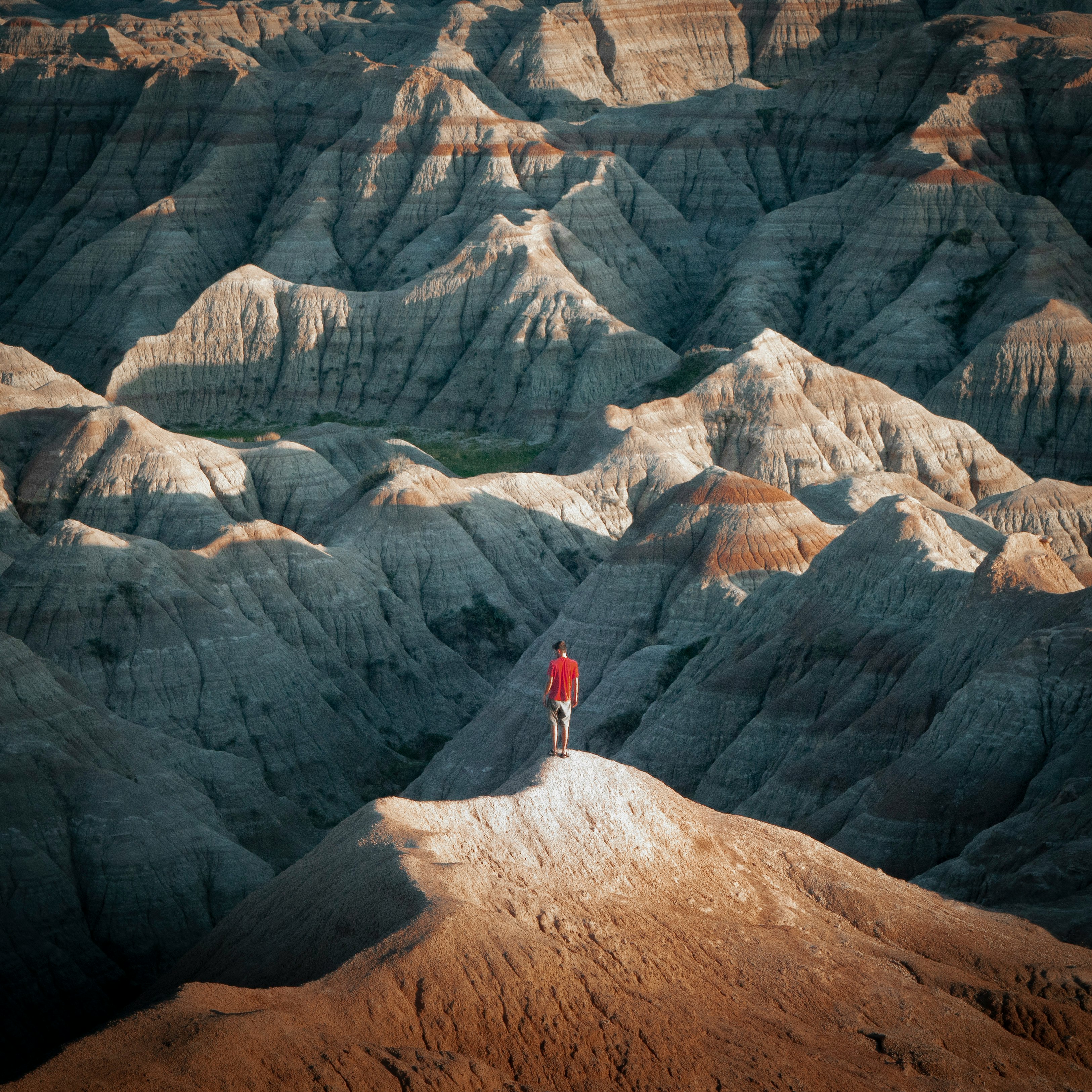 person in red jacket standing on brown rock mountain during daytime