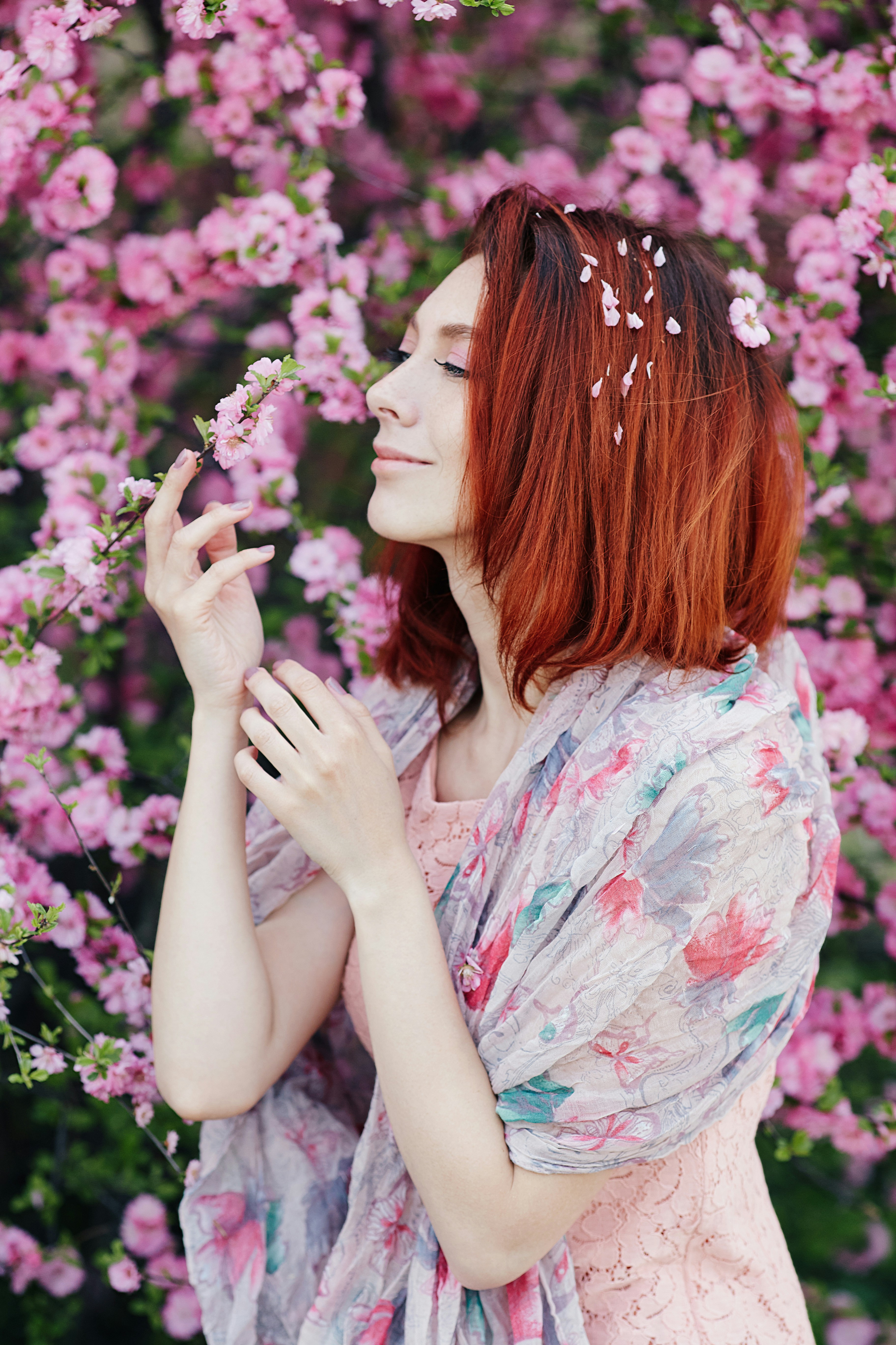 Portrait of a fair-haired girl in a blooming garden. The young woman's short, fiery hair is covered in flower petals. A delicate spring portrait for the website and social networks. Автор - фотограф Олег Мороз (Tengyart)