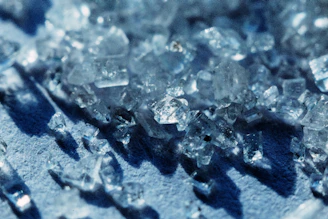 Close-up of shimmering crystals growing inside a high-tech laboratory chamber with soft blue lighting.