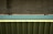 A close-up view of a bridge structure featuring a concrete support and a metal beam with a teal colored surface in between. The photo highlights the geometric patterns and textures of the materials used in the construction.
