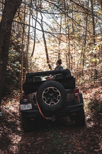 man in black jacket sitting on black jeep wrangler