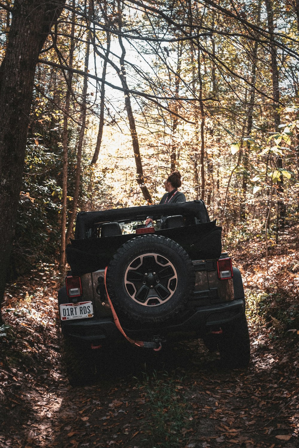 Homme en veste noire assis sur une Jeep Wrangler noire