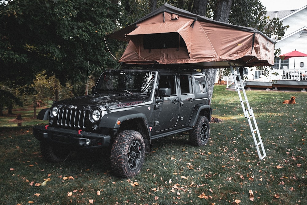 Schwarzer Jeep Wrangler parkt tagsüber in der Nähe eines braunen Holzhauses