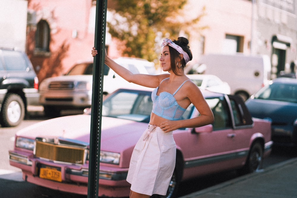 woman in white spaghetti strap dress standing beside black car during daytime