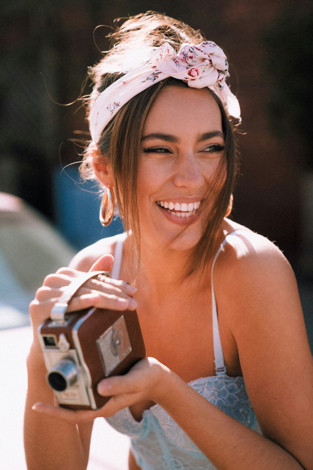 smiling woman in white tank top holding black smartphone