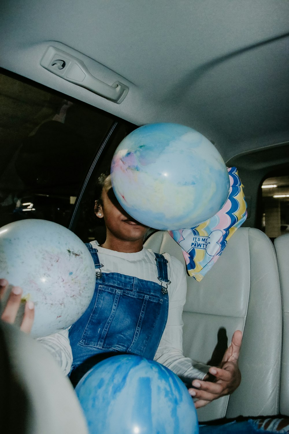 boy in blue denim dungaree holding white and blue globe