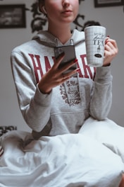 A cheerful university student happily checking bedspace listings on a smartphone in a cozy room.