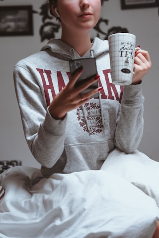 A cheerful university student happily checking bedspace listings on a smartphone in a cozy room.