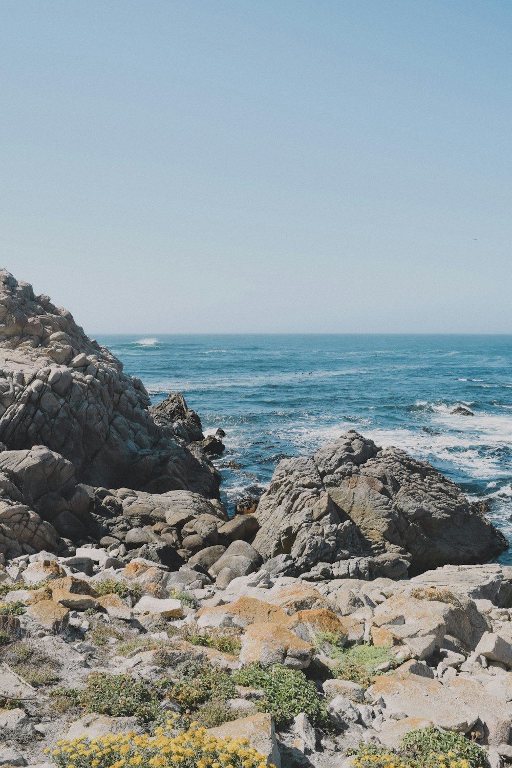 rocky shore with ocean waves crashing on shore during daytime