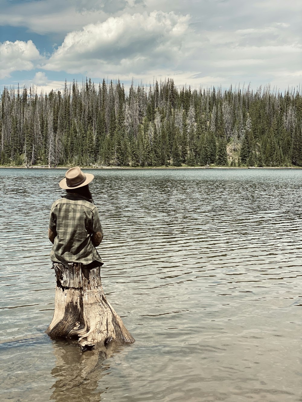 갈색 모자를 쓴 남자가 낮 동안 물에 갈색 나무 통나무에 서 있다