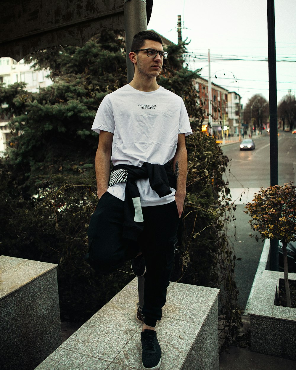 man in white crew neck t-shirt and black pants sitting on black concrete bench during
