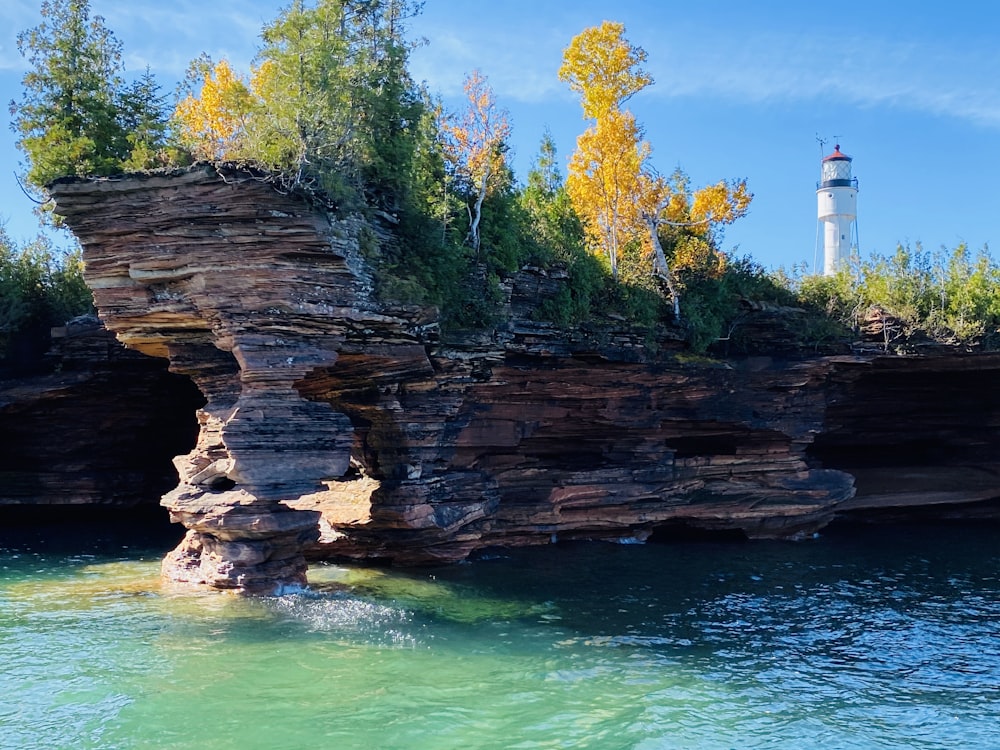 white lighthouse near green trees and body of water during daytime