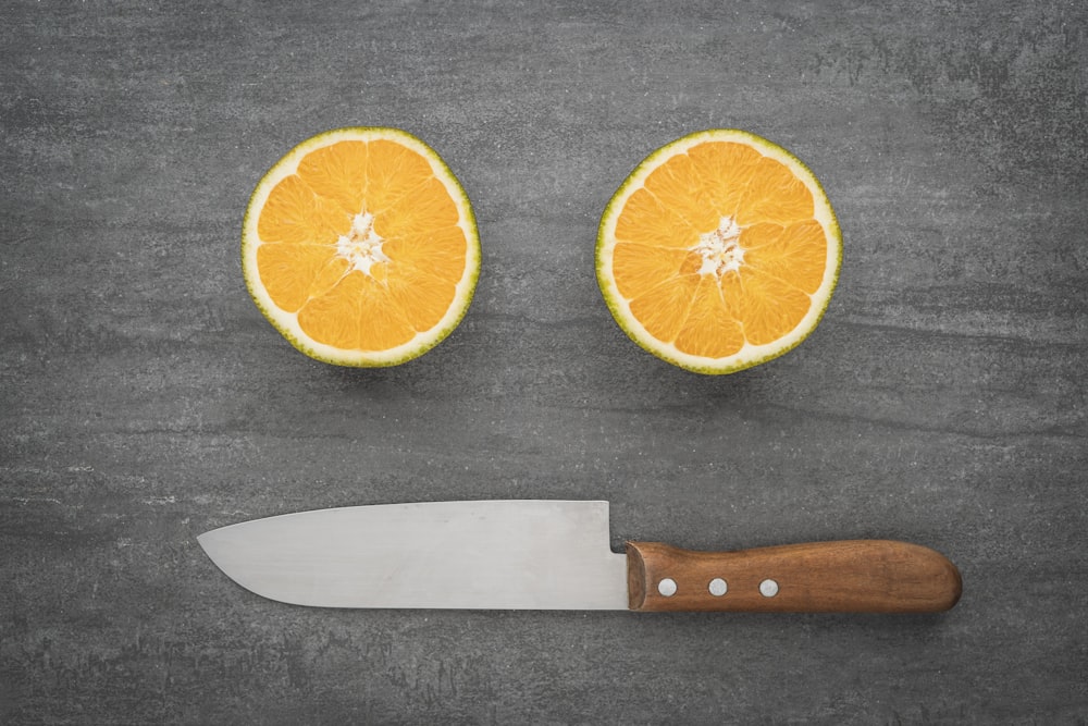 sliced orange fruit beside black handled knife