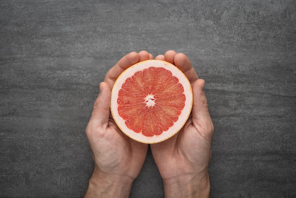 person holding orange citrus fruit