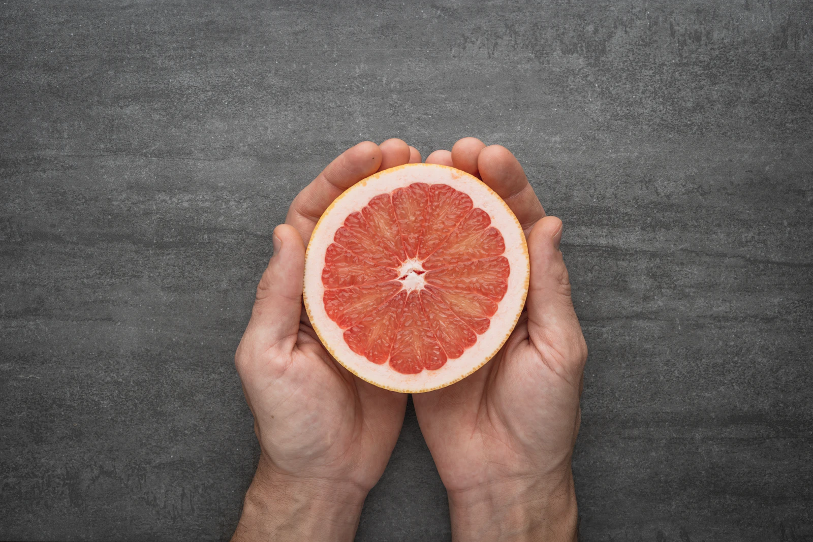 Hands holding a fresh orange citrus fruit