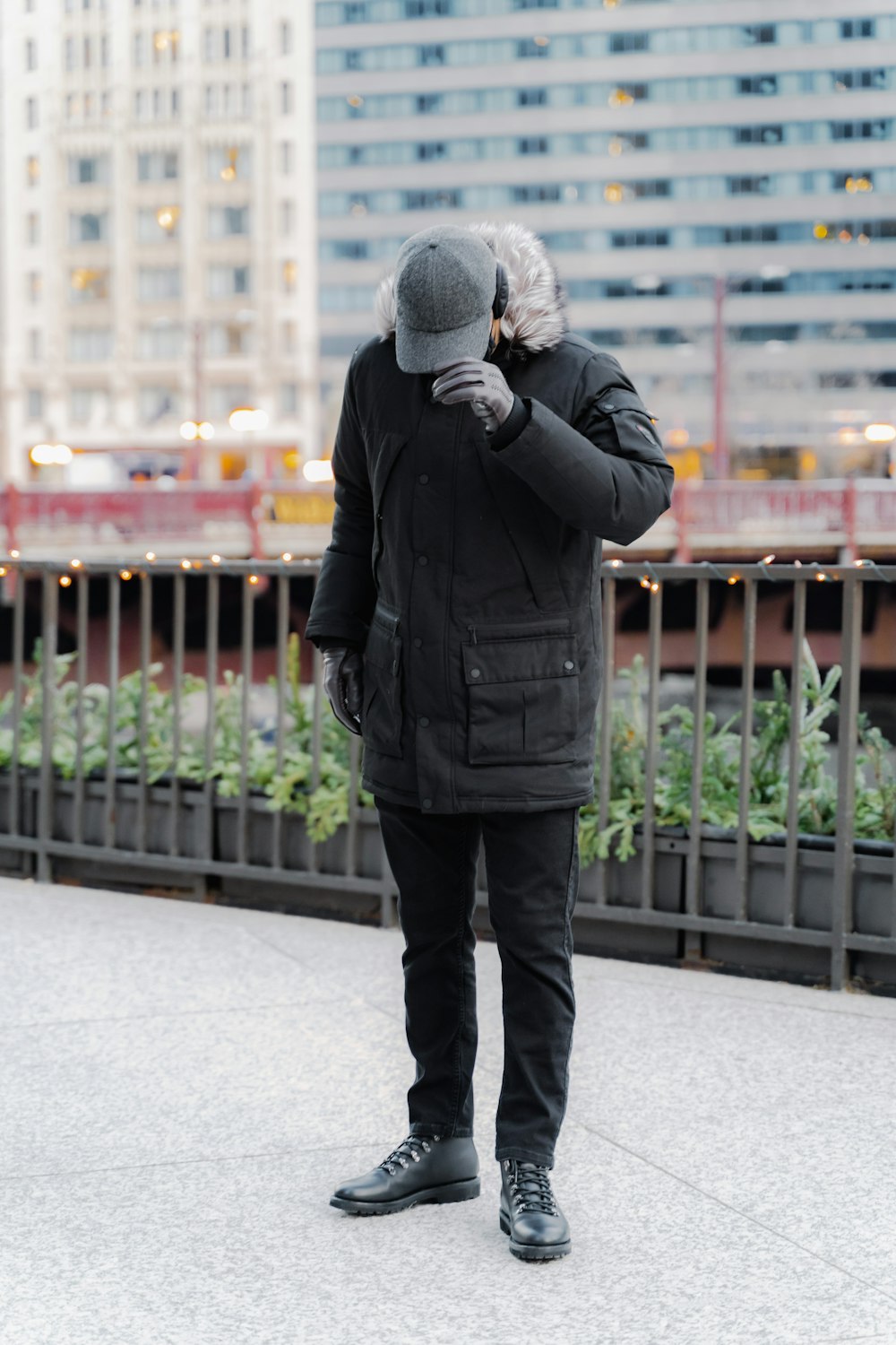 man in black jacket and black pants standing on sidewalk during daytime