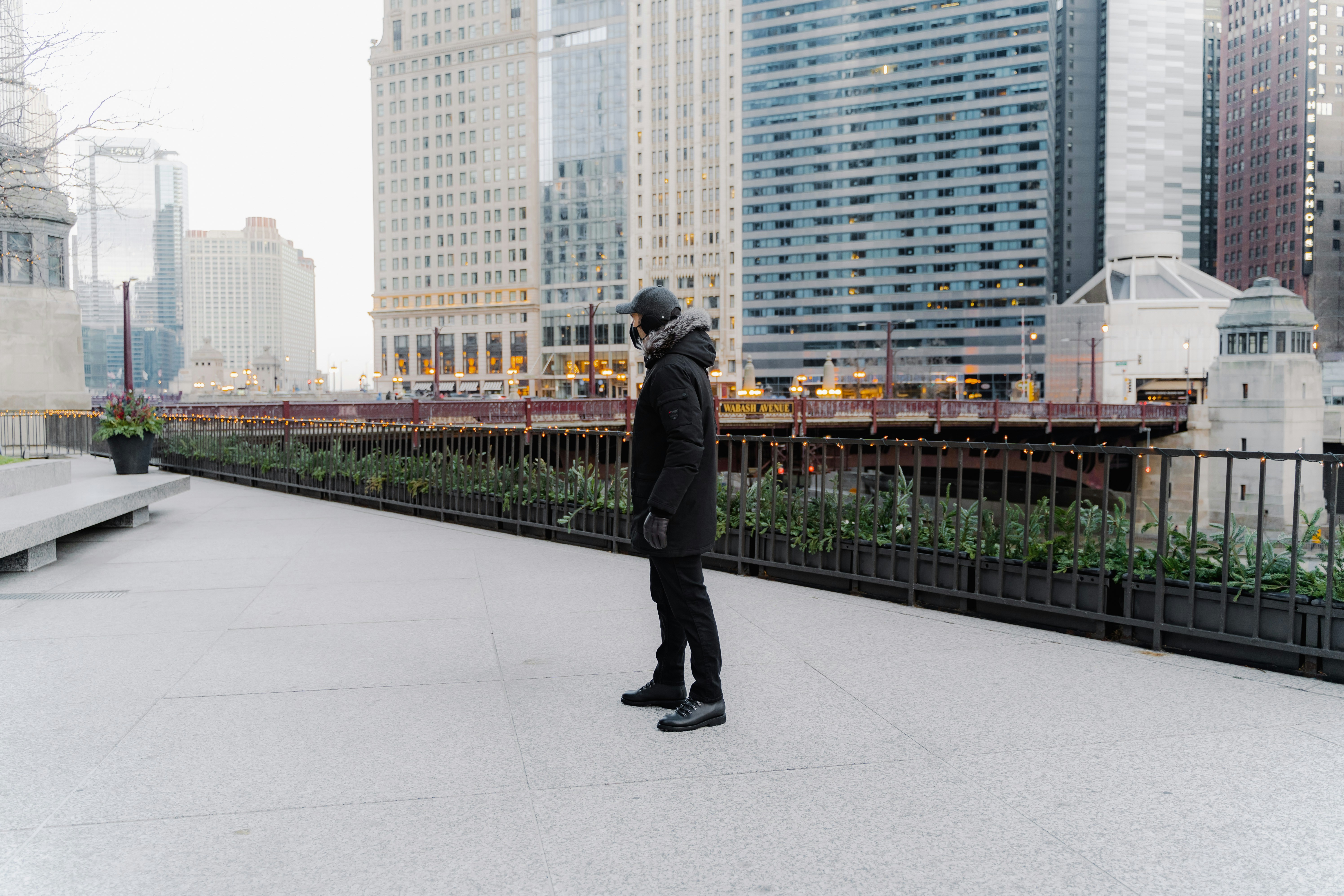 Dapper Professional styling a Vandre wool hat wearing a mask, winter parka coat, denim and black boots downtown Chicago.