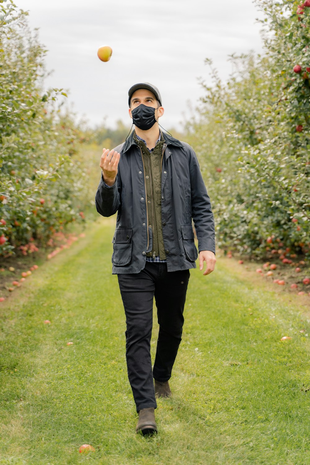 man in black leather jacket and black pants standing on green grass field during daytime