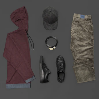 Minimalist flat lay of unisex fashion accessories including bags, slides, and jewelry on a white background.