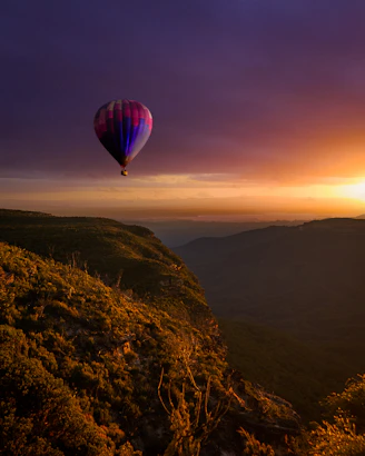 hot air balloon flying over the mountains during sunset