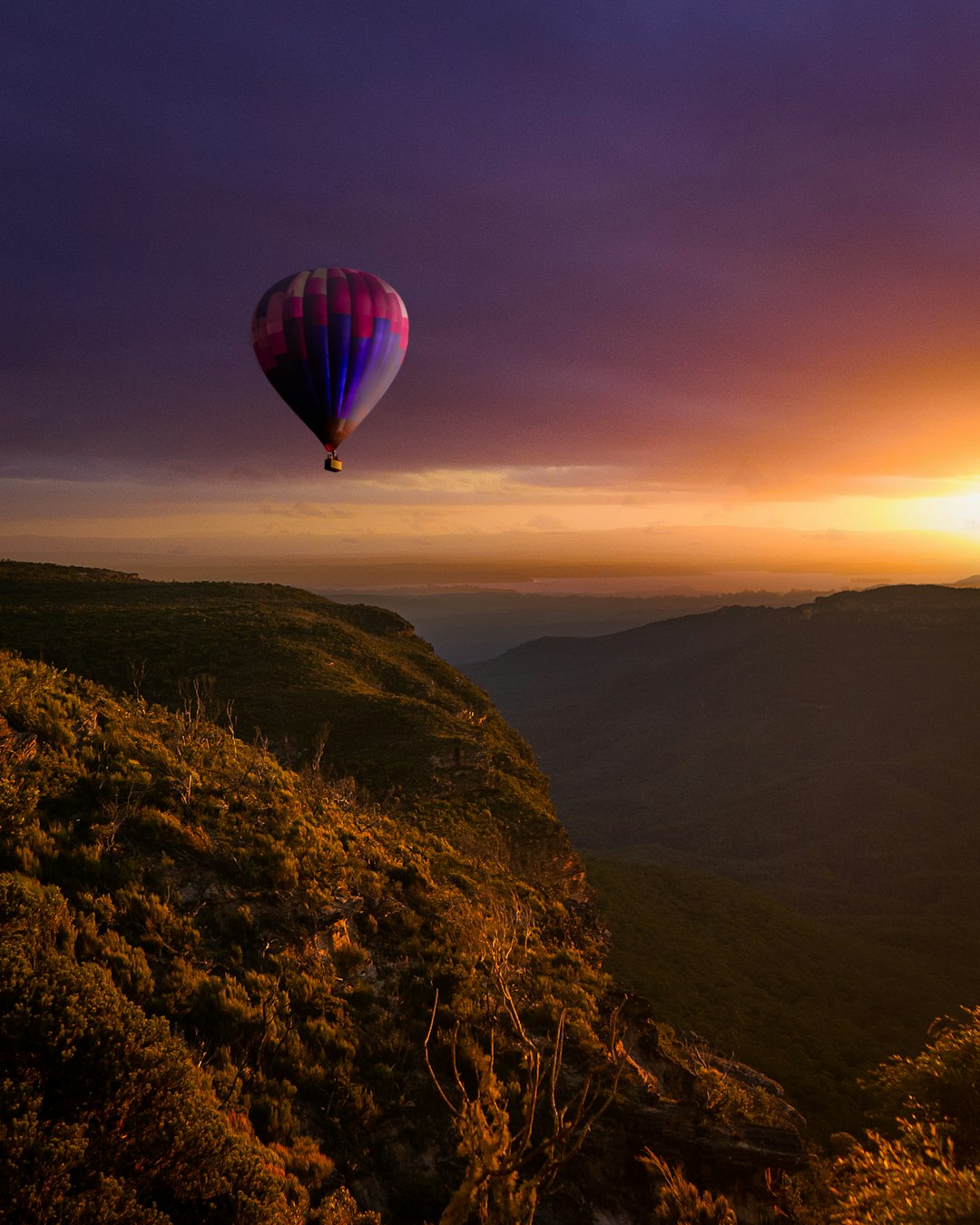 hot air balloon flying over the mountains during sunset