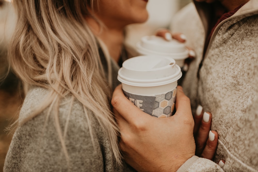 woman holding white and blue disposable cup