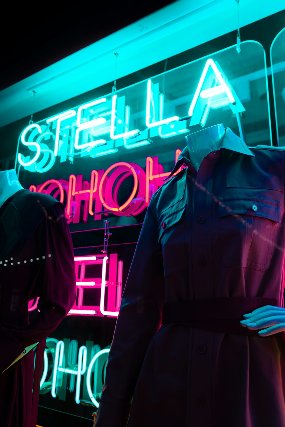 man in black coat standing near blue and white open neon signage
