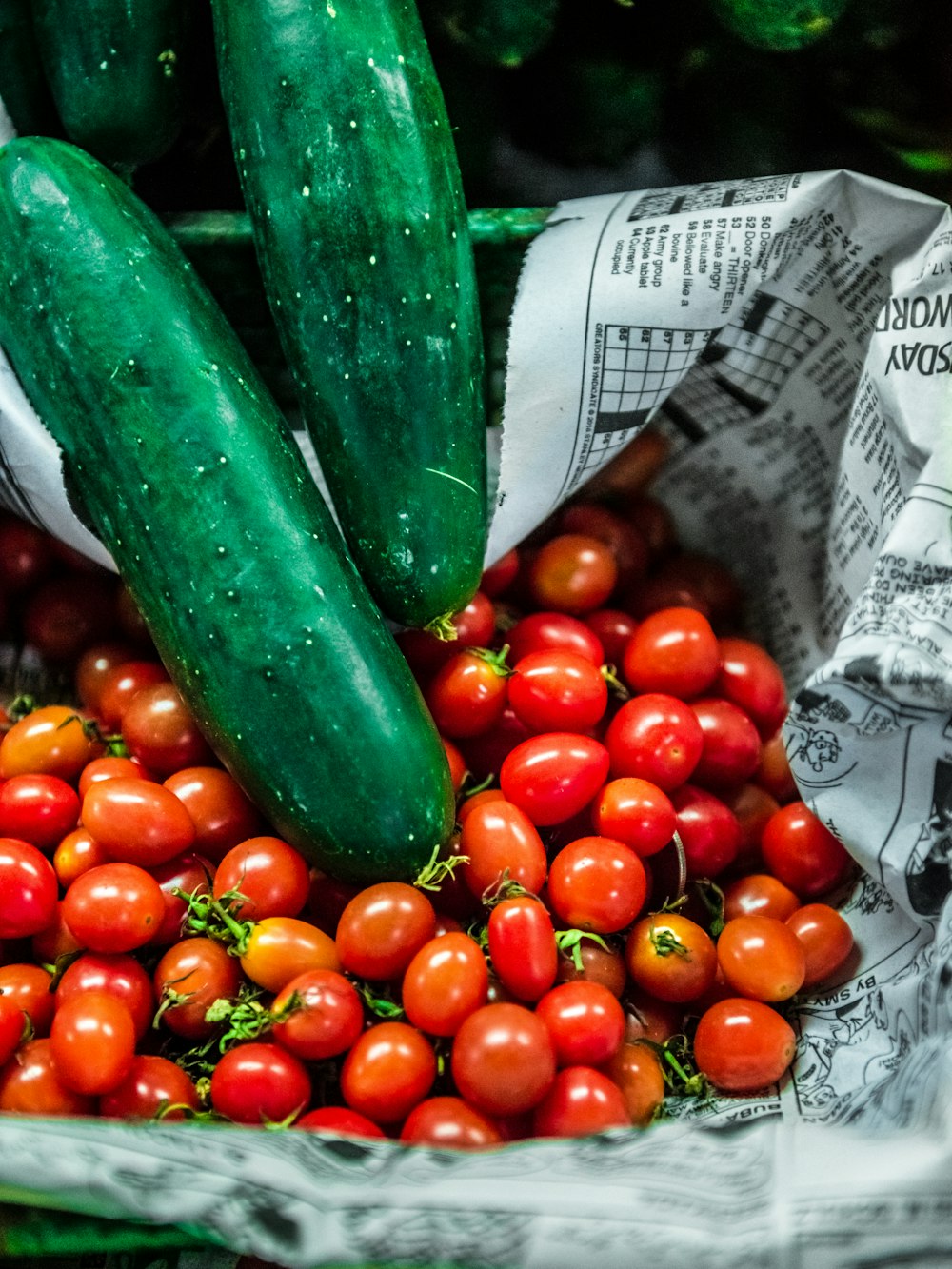 Pepino verde sobre textil con estampado de frutos blancos y rojos