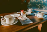 A bright, sunlit table set with cheerful ceramic plates and cups ready for a slow morning.