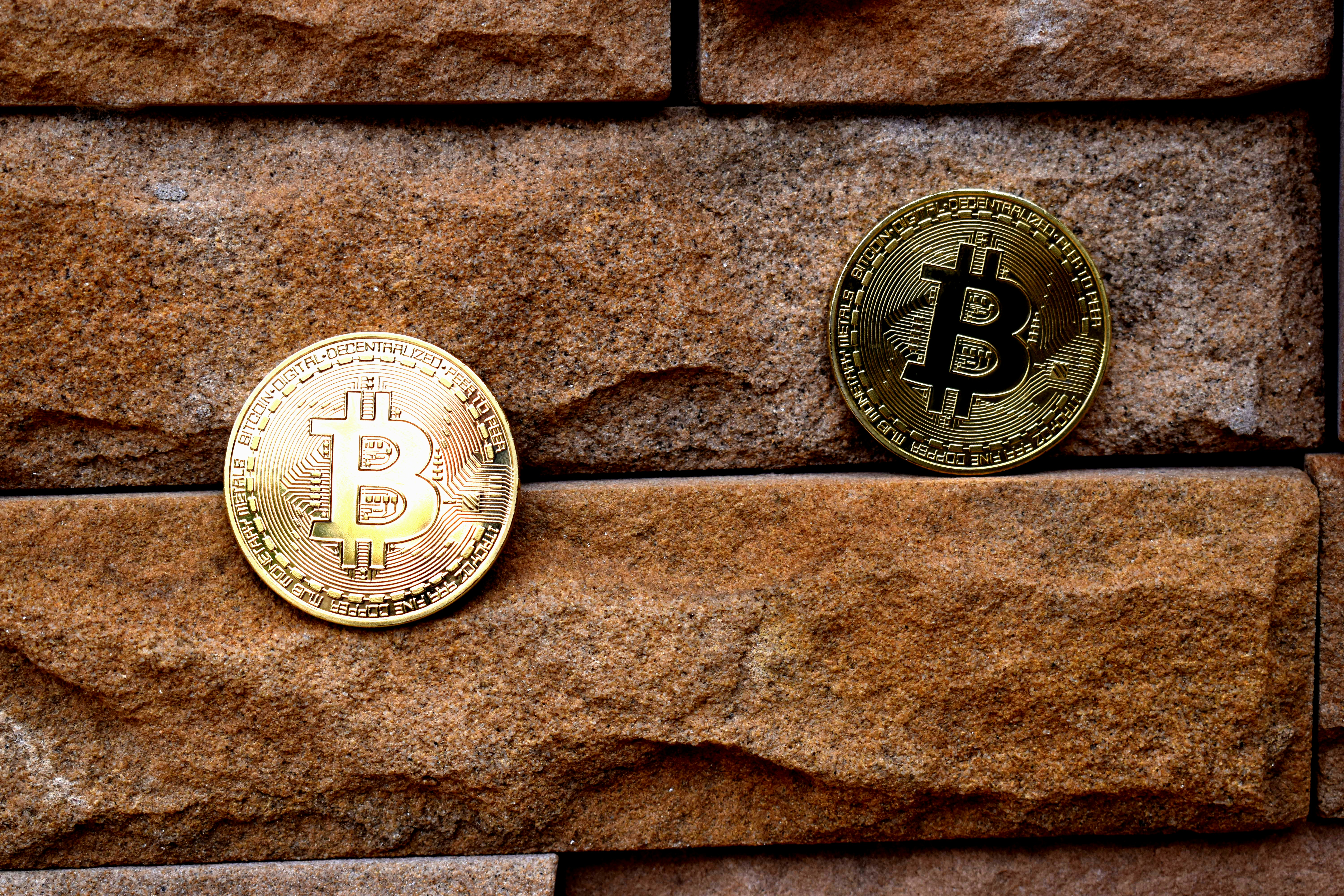 Two Bitcoins lining the cracks of a brick wall.