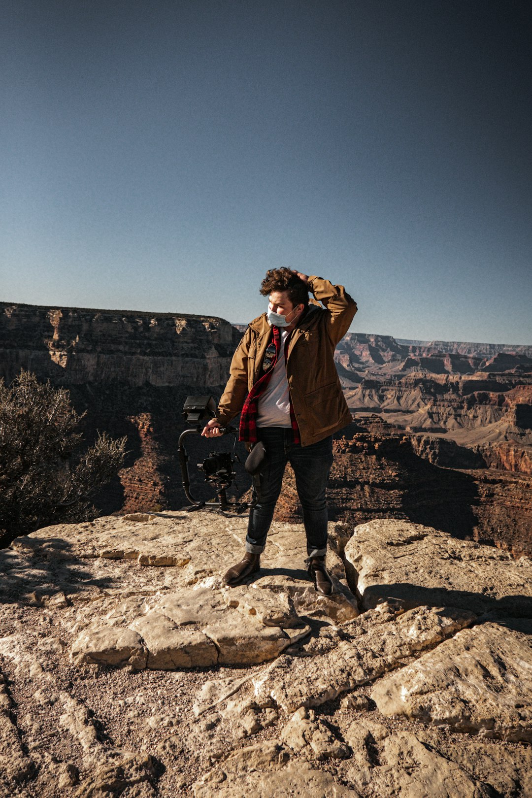 woman in brown jacket and black pants standing on rock formation during daytime