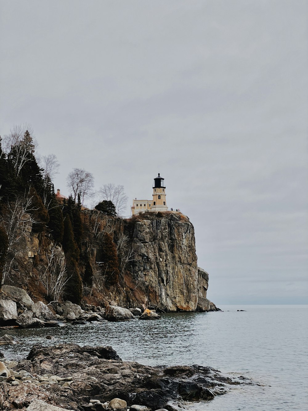 white lighthouse on brown rock formation near body of water during daytime