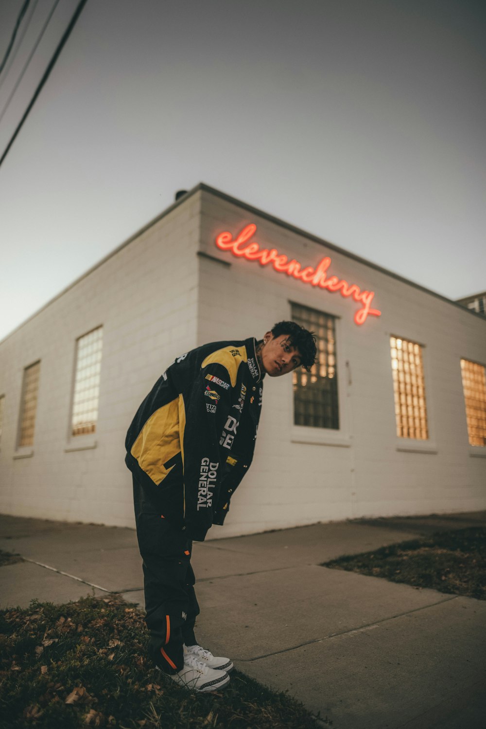 man in black and yellow jacket standing on sidewalk during daytime