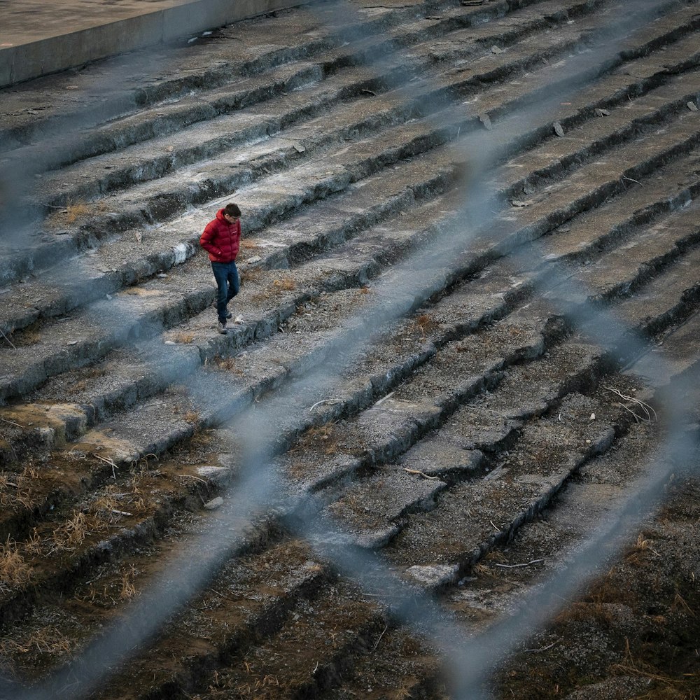 child in red hoodie standing on gray sand during daytime