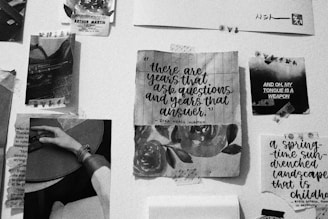 A collage of black-and-white photographs, text, and artwork pinned to a wall. The centerpiece features a quote by Zora Neale Hurston overlaid on a floral background. Nearby are various clippings, including images of a person holding a guitar and abstract text art with phrases like 'AND OH, MY TONGUE IS A WEAPON.'