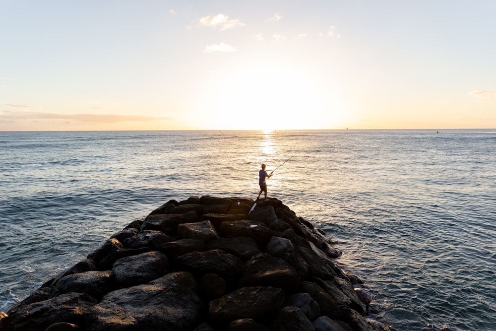 person standing on rocky shore during daytime