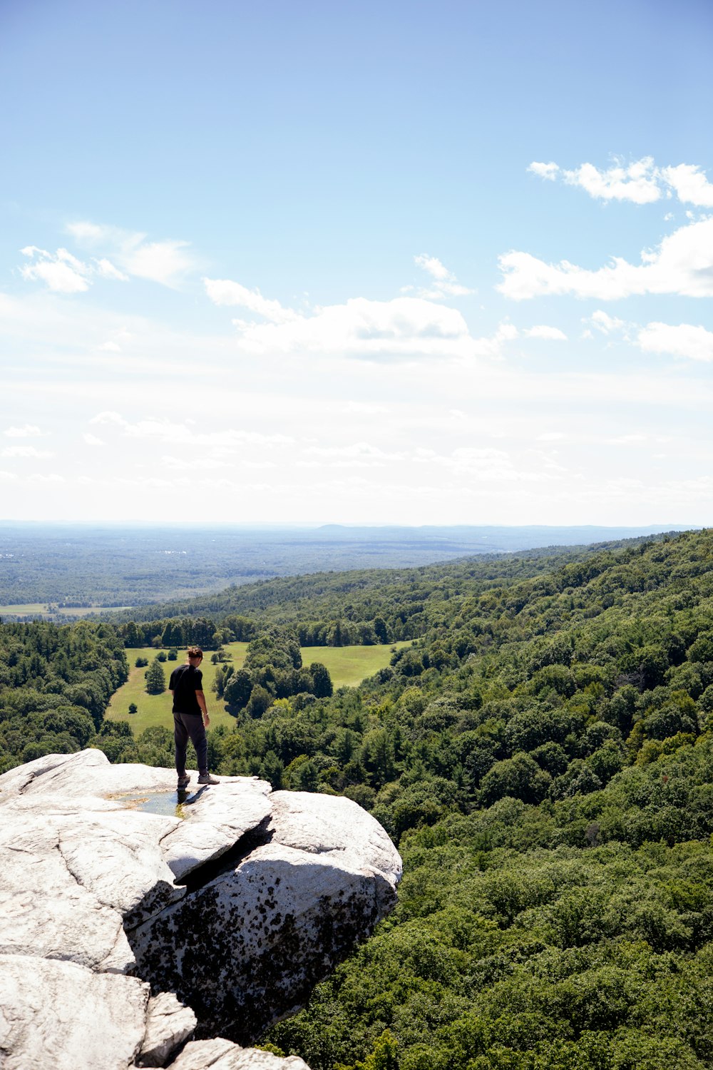 person standing on rock near green grass field during daytime