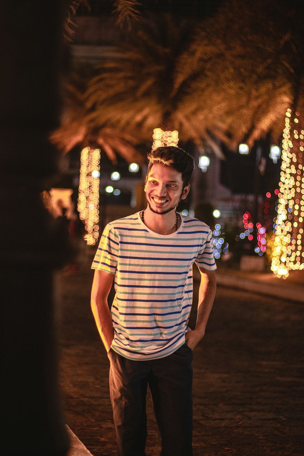man in white and black striped crew neck t-shirt standing near christmas tree