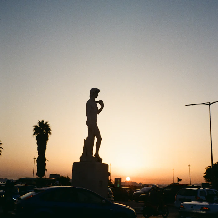 silhouette of man standing on street light during sunset