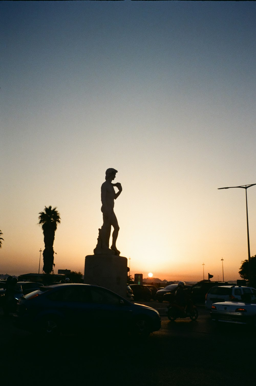 silhouette of man standing on street light during sunset