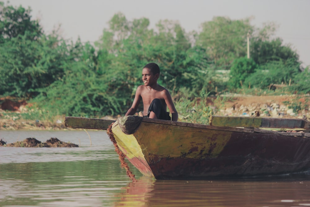 Mann in braunem Boot tagsüber auf dem Fluss